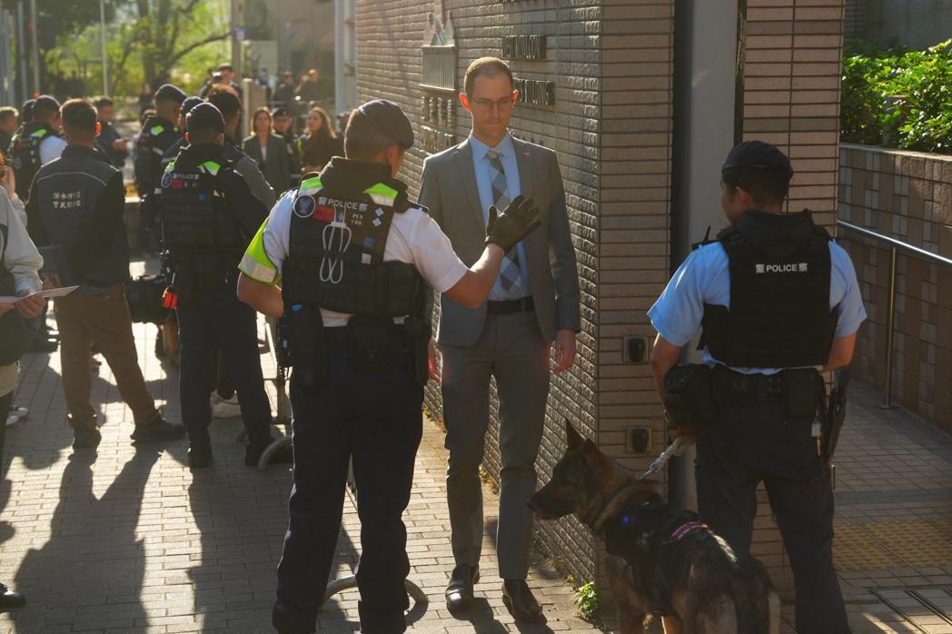 黎智英国安案即将宣判,西九龙裁判法院外香港警方如临大敌。图为一名美国领事代表排队... 黎智英国安案即将宣判,西九龙裁判法院外香港警方如临大敌。图为一名美国领事代表排队...