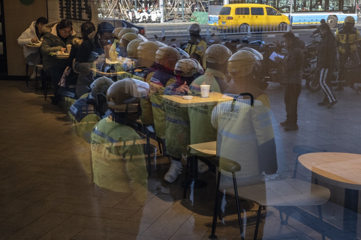 美团外卖骑手在北京一家麦当劳餐厅外站队。