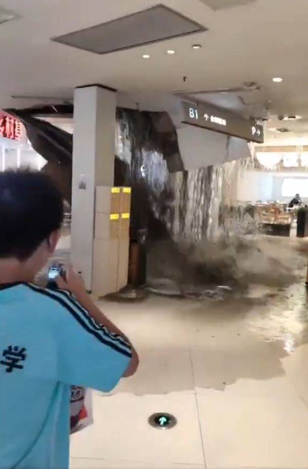 重庆一间商场因为扛不住暴雨，天花板突然垮下，大量雨水挟带泥沙倾泻而下，卖场中的顾客惊呼连连，四下奔逃。（撷取自微博）