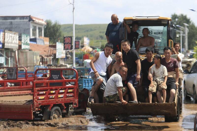 图为中国辽宁省葫芦岛市遭逢暴雨肆虐，建昌县黑山科乡灾民在雨后泥泞中靠推土机疏散。（美联社资料照）