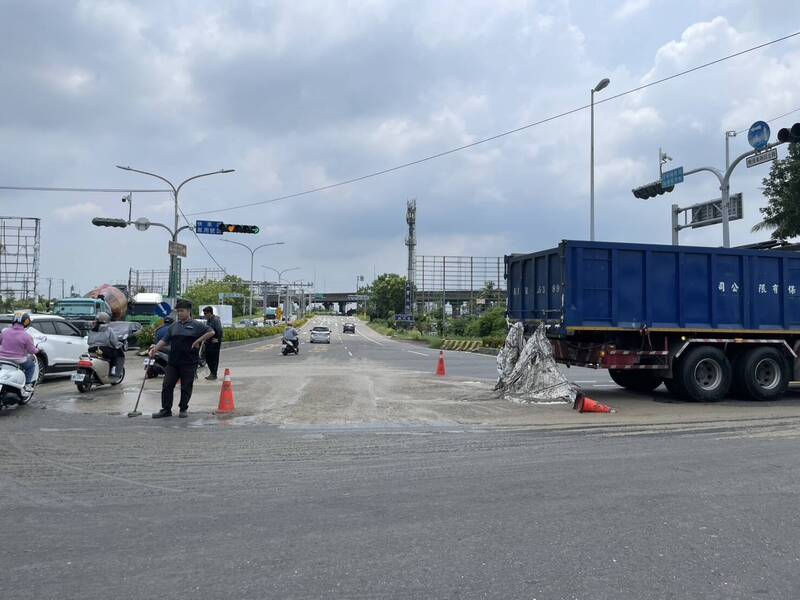 台南新市區新港社大道通往國8路口，25日一輛環保公司載送的污泥散落一地，用路人抱怨臭氣薰天，廠商調派人員清理現場。（讀者提供）