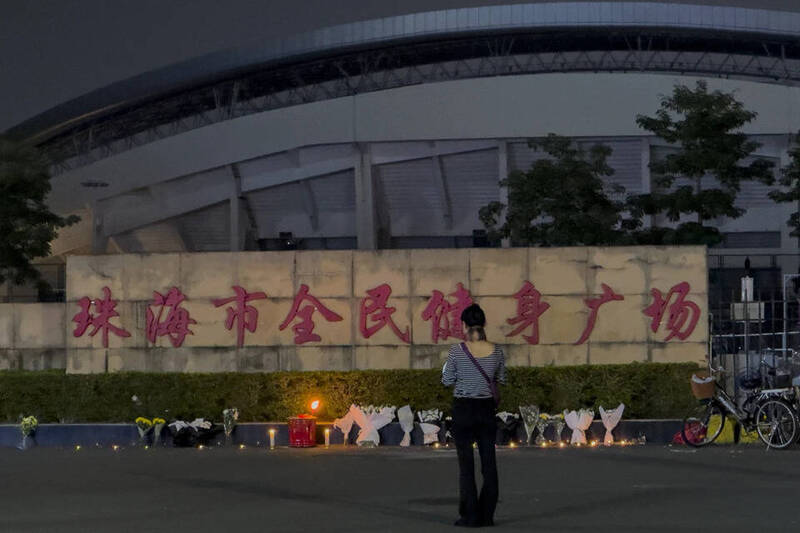 1名女子站在擺滿鮮花與蠟燭的「珠海市全民健身廣場」前，悼念2024年11月12日遭駕車衝撞事件中的死傷者。當時1名男子故意駕車沖入正在運動的人群，造成多人死傷。（美聯社）