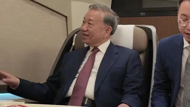 苏林(左)在北京开往雄安高铁列车上打量车厢(中国中央电视台片段截屏 14/4/2026)