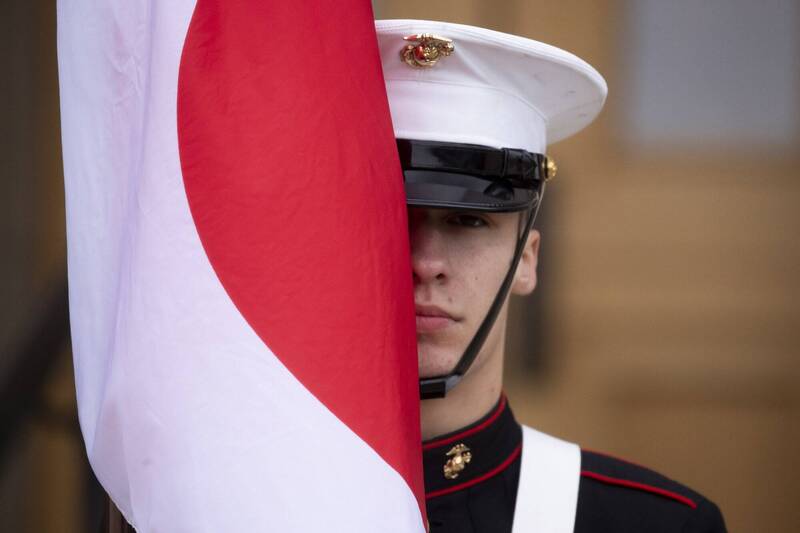 多名消息人士25日透露,日本政府已开始研拟以日方承担费用的方式,加强美军设施防护的方案。图为手举日本国旗的美军士兵。 (欧新社资料照)