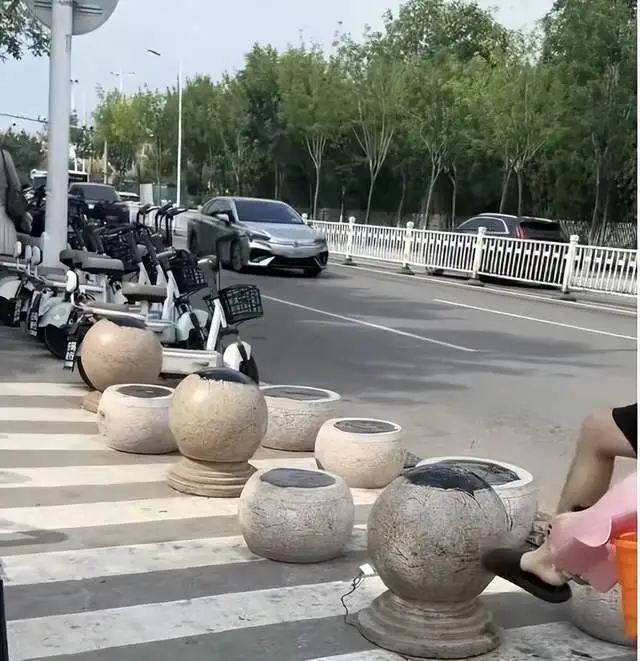 海水浴场门口隔离石墩被涂抹沥青 游客带娃被粘上